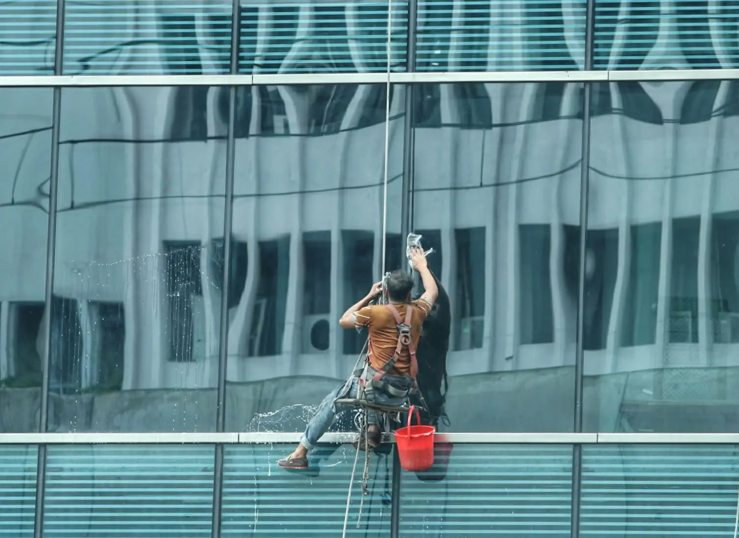 বহুতল ভবনের কাঁচ পরিষ্কার করেছেন এক শ্রমিক