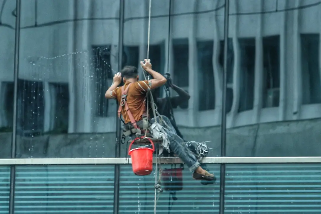 বহুতল ভবনের কাঁচ পরিষ্কার করেছেন এক শ্রমিক