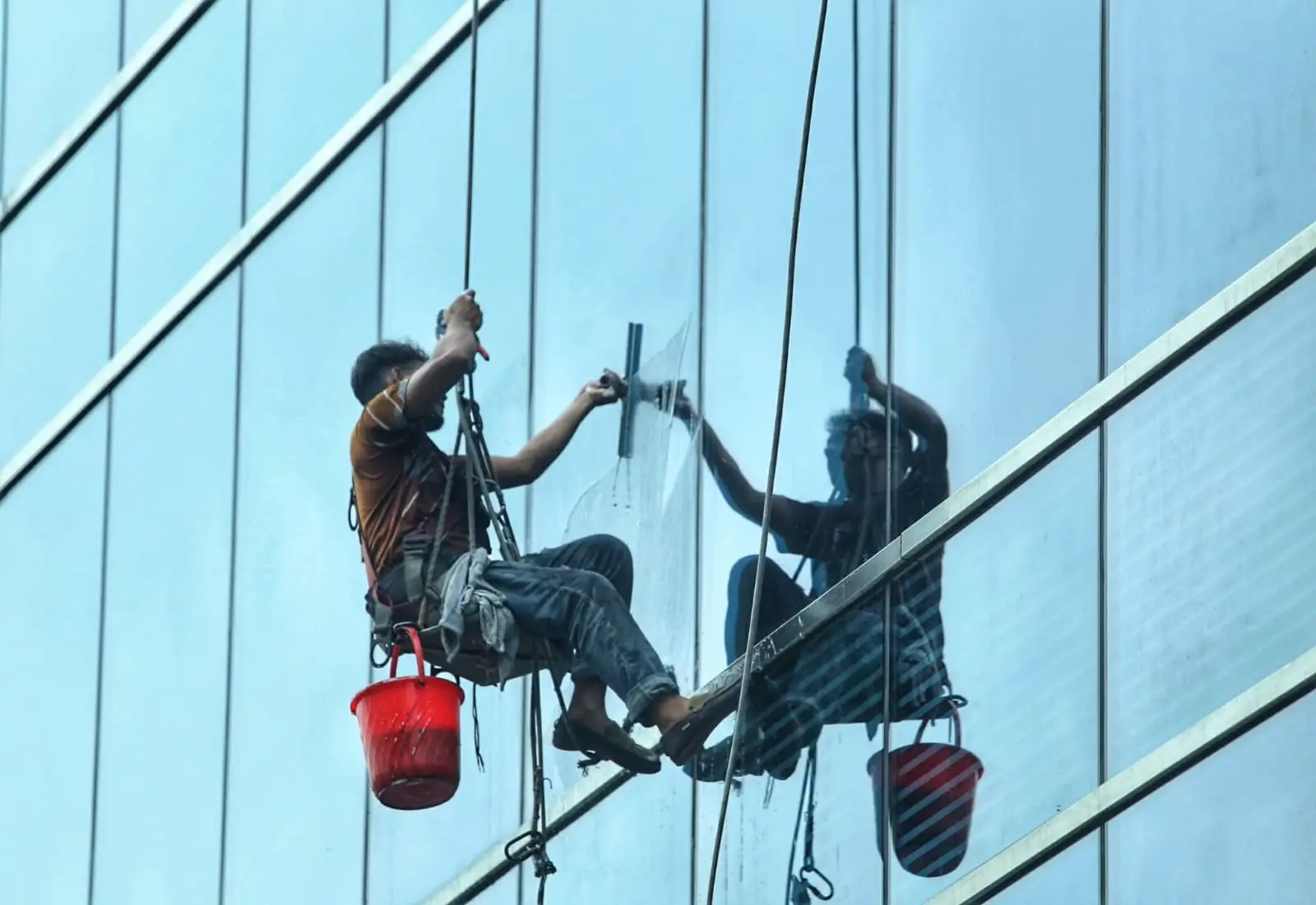বহুতল ভবনের কাঁচ পরিষ্কার করেছেন এক শ্রমিক